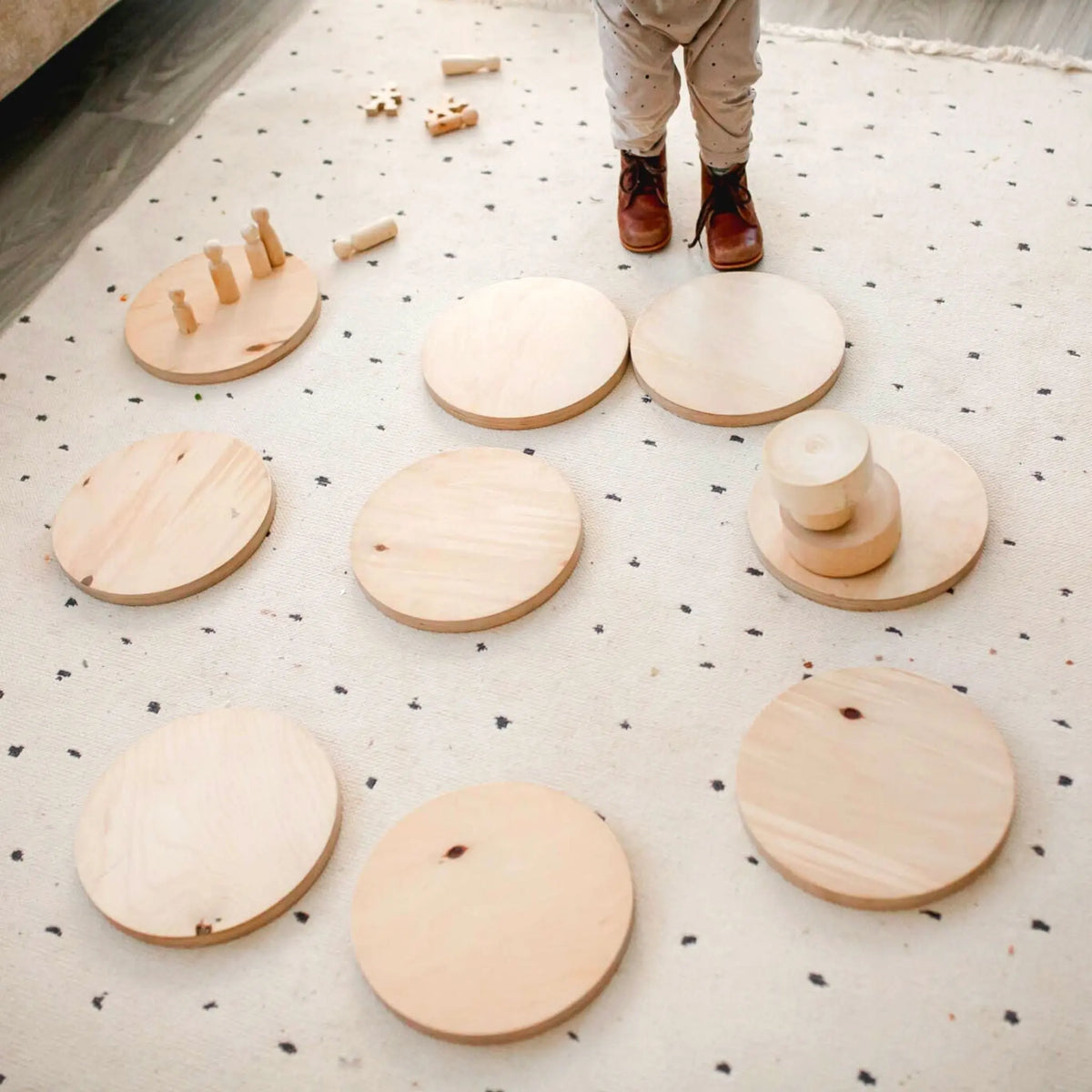 Pale round stepping stones arranged among small toy blocks, with a child standing behind them.