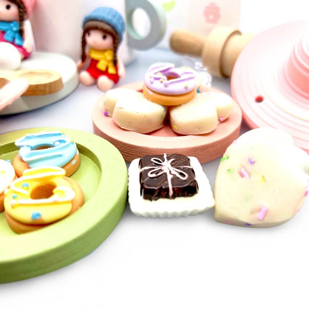 Miniature donuts and chocolate pastry beside playdough treats; pink tea-party hat not included