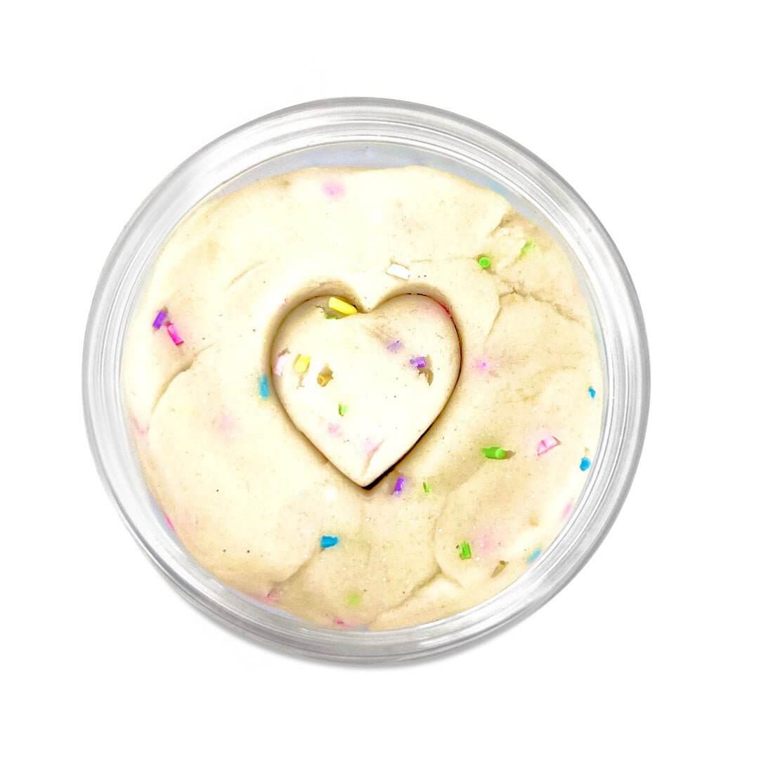 Heart-shaped impression in cream-colored playdough with colorful sprinkles inside a jar
