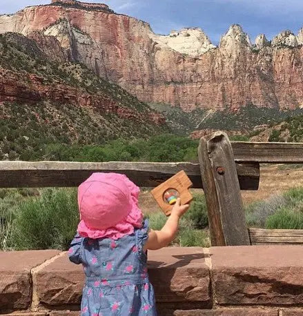 Child holding a wooden rattle at an outdoor scenic overlook