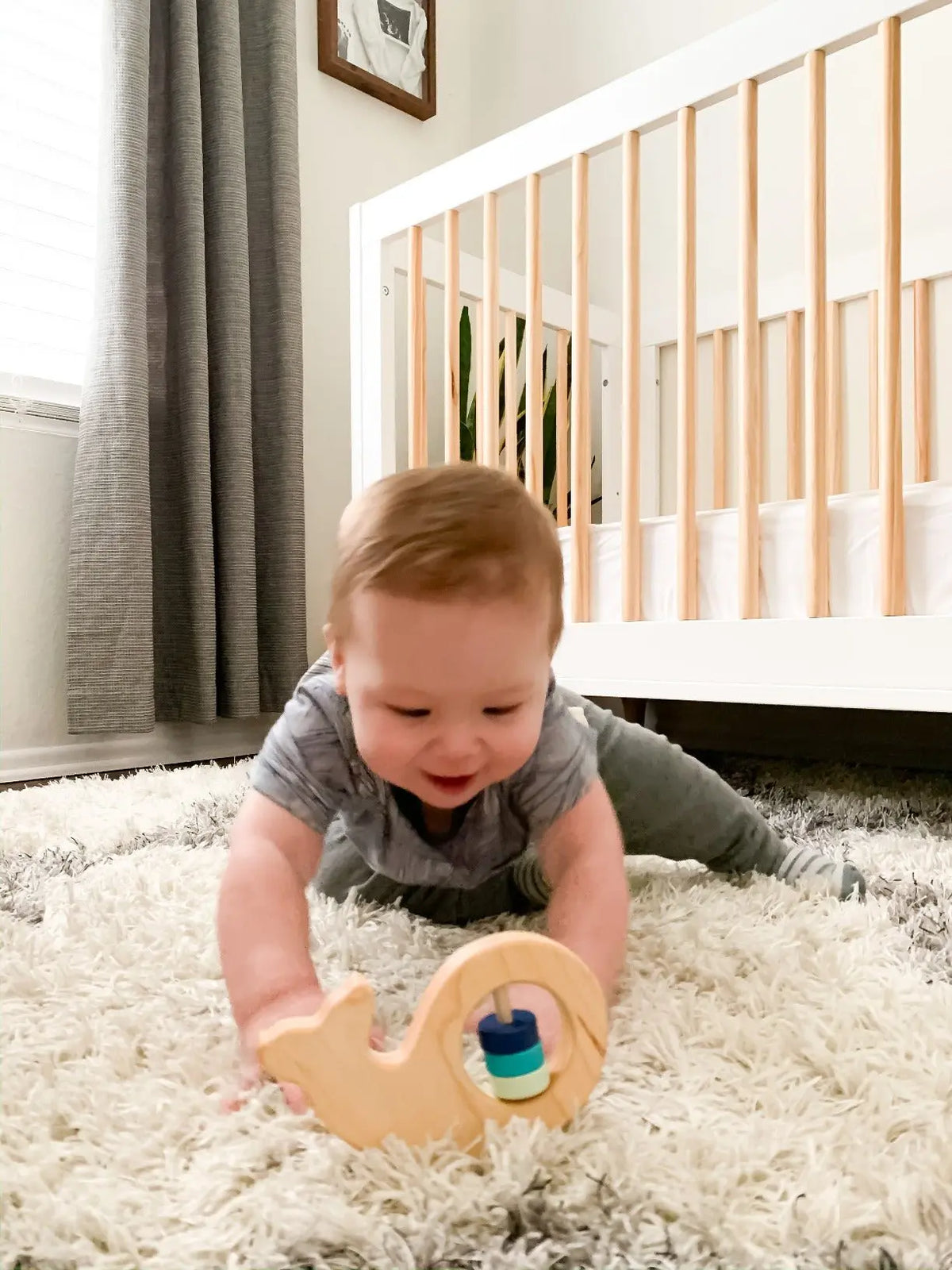 Lifestyle photo showing a wooden baby rattle with a child