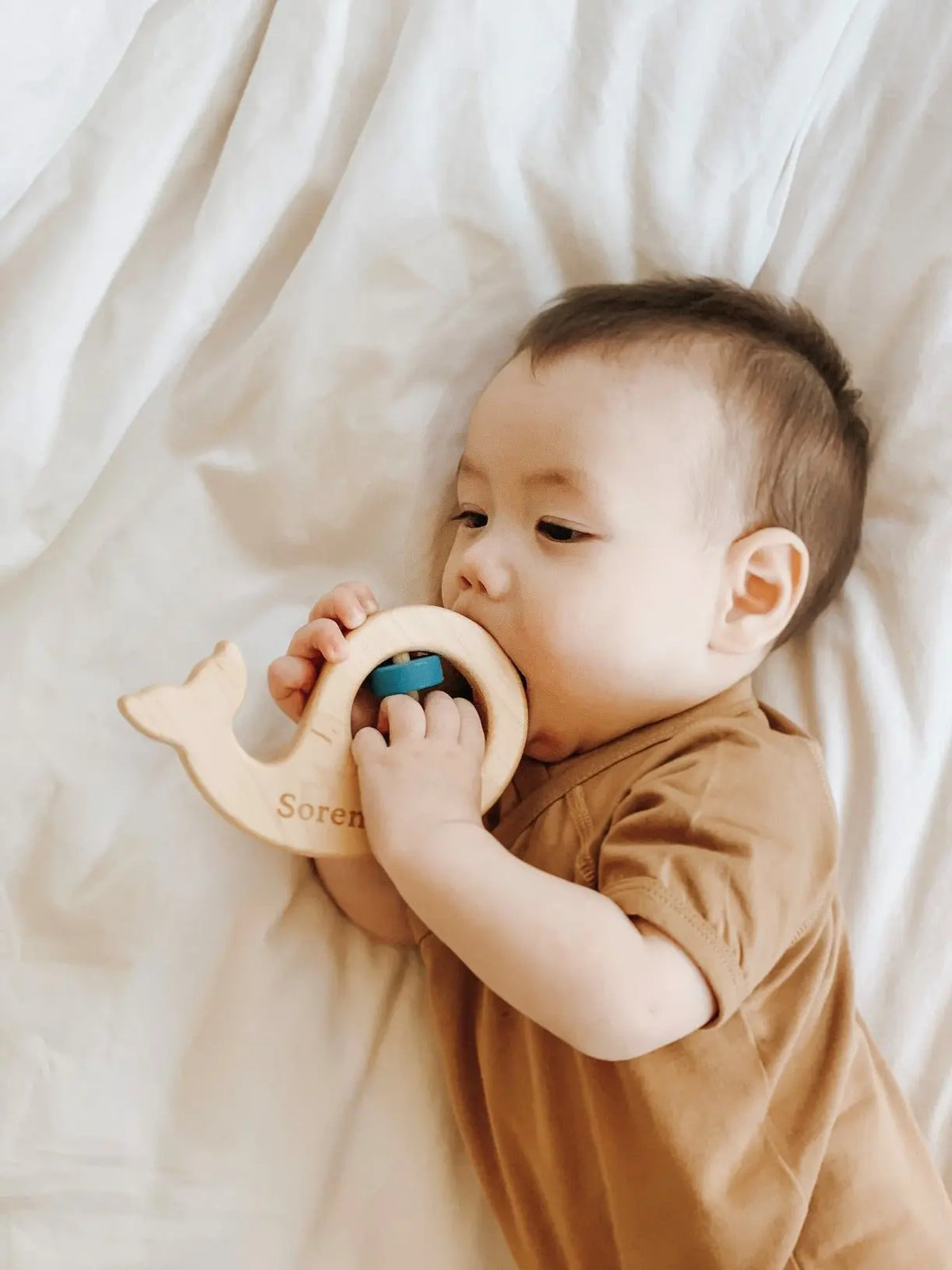 Lifestyle photo showing a wooden baby rattle with a child