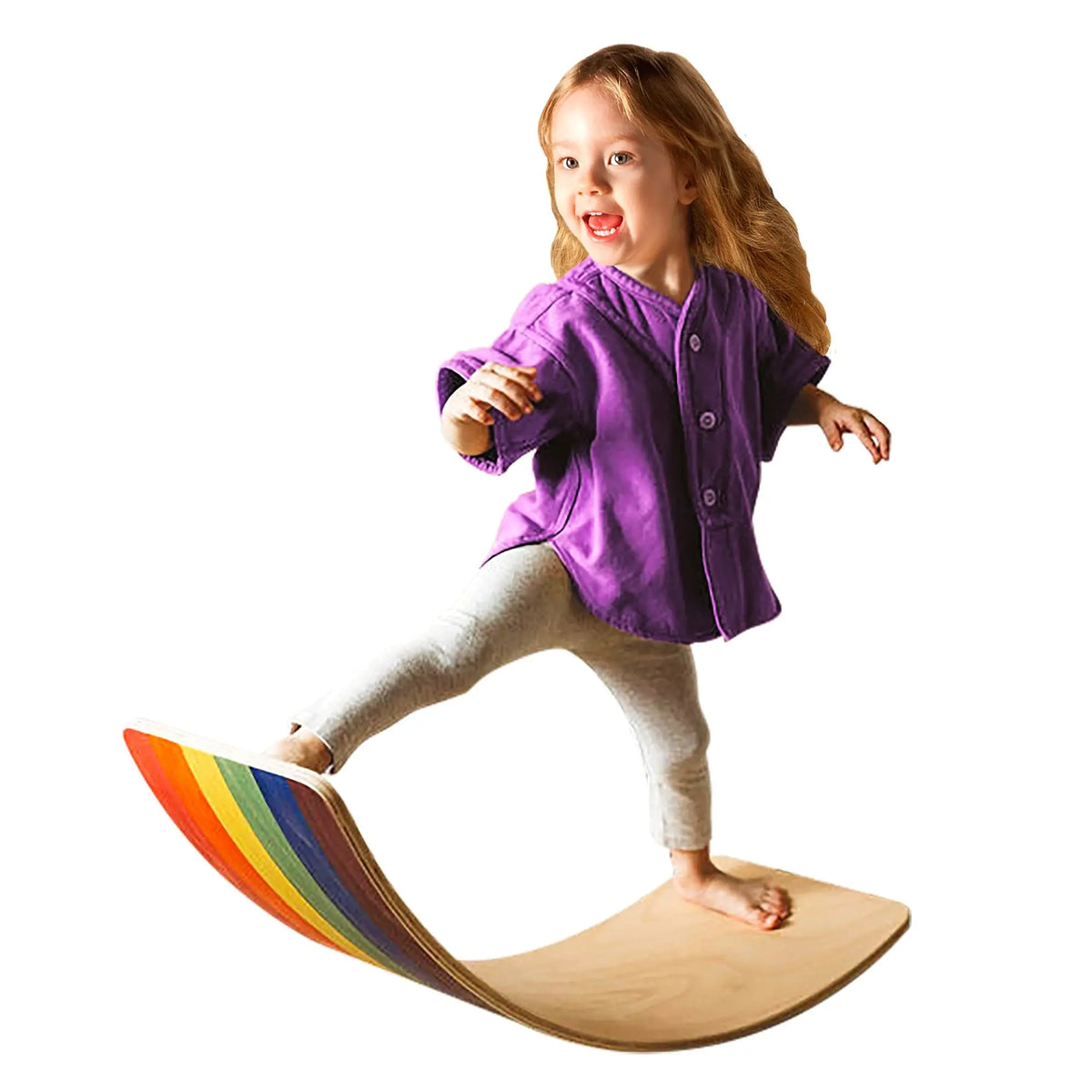 Child balancing on a curved wobble board with a natural-tone top and rainbow-striped outer face.