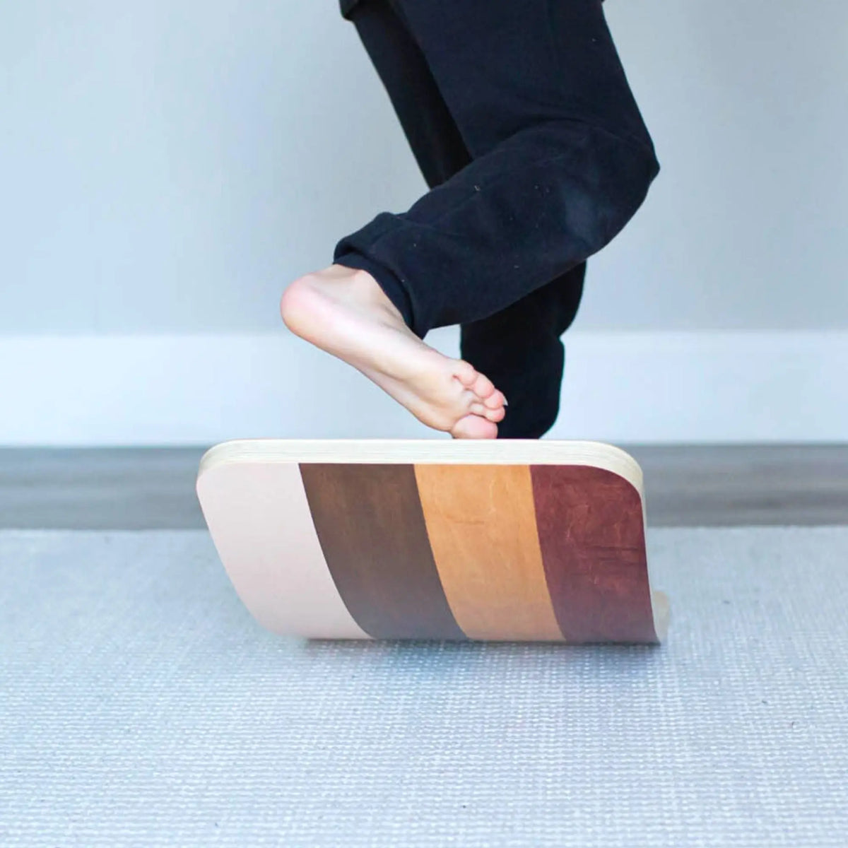 Close-up of bare feet above a cream-and-brown-striped wobble board.