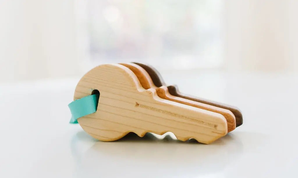 Three wooden toy keys in different natural wood colors joined by an aqua strap