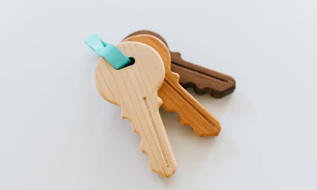 Wooden toy keys spread apart to show their shapes and aqua connecting strap