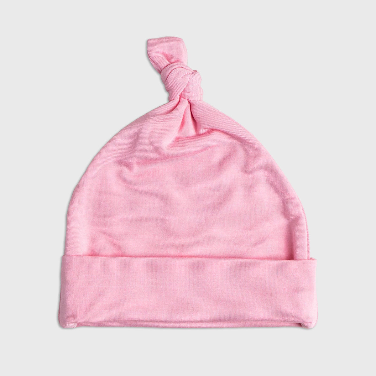 Flat lay of Bam & Stitch Pink Blossom Hat, showing the top knot and folded brim.