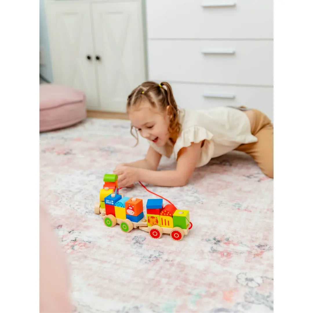 SpiritnSprout: Child rolling the stacked train along a rug