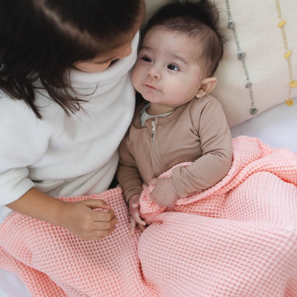 SpiritnSprout: Older child leaning toward a baby on the rose pink blanket