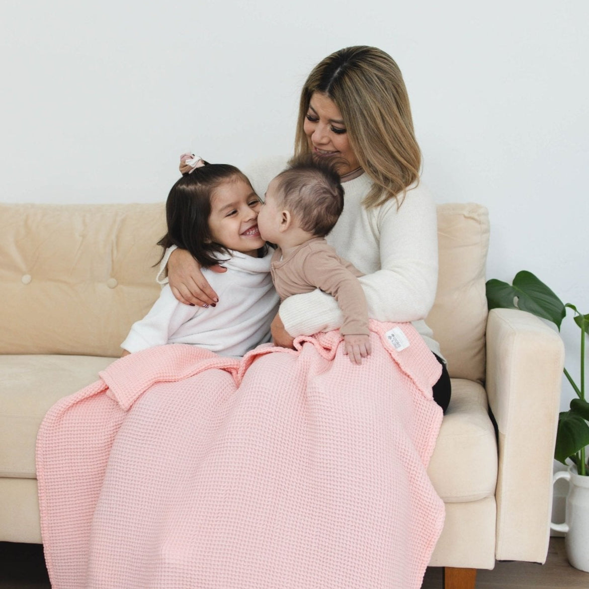 SpiritnSprout: Caregiver and two children sitting together with a rose pink blanket